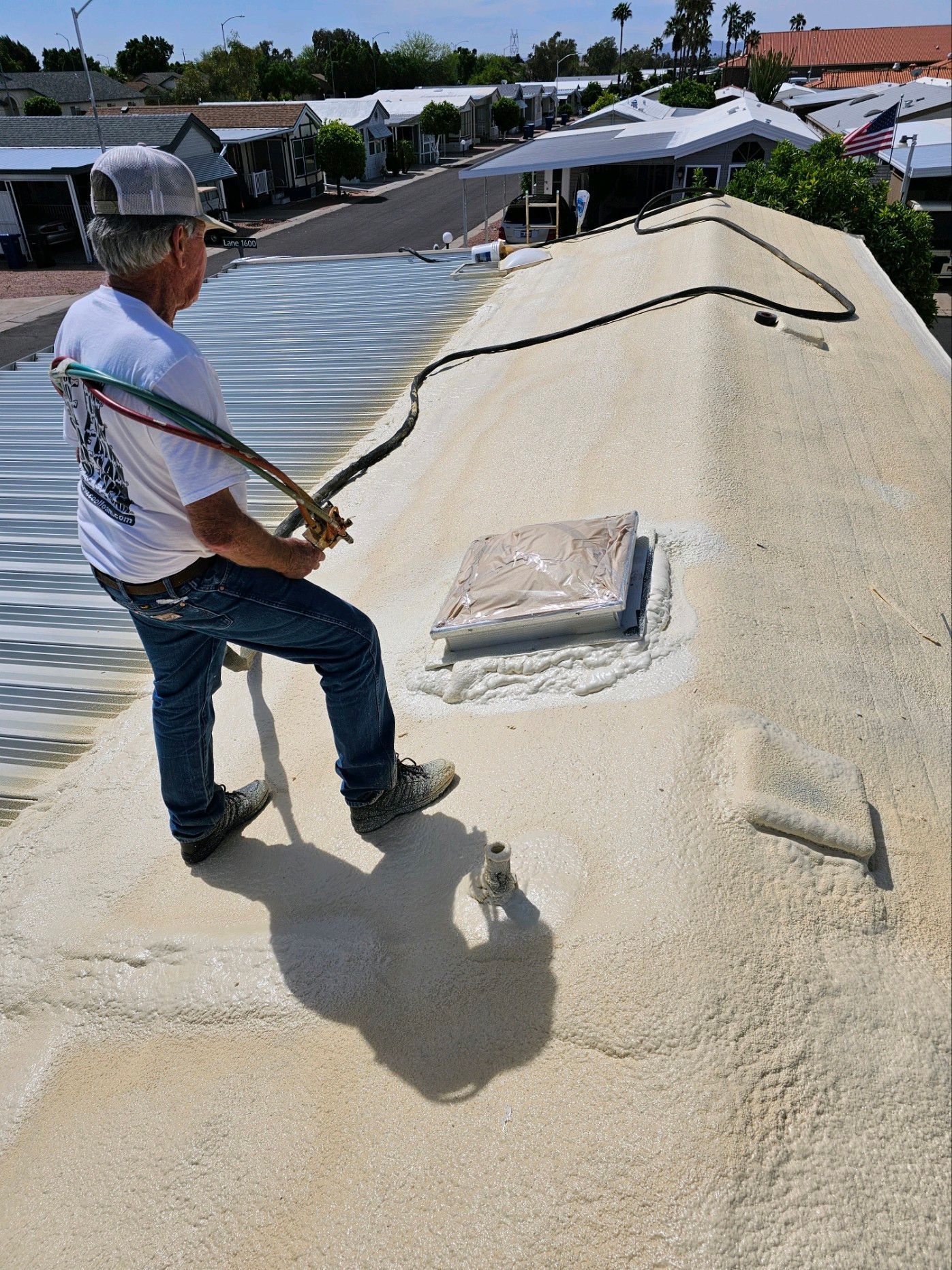 Worker inspecting a rooftop covered with light-colored insulation under bright sunlight.
