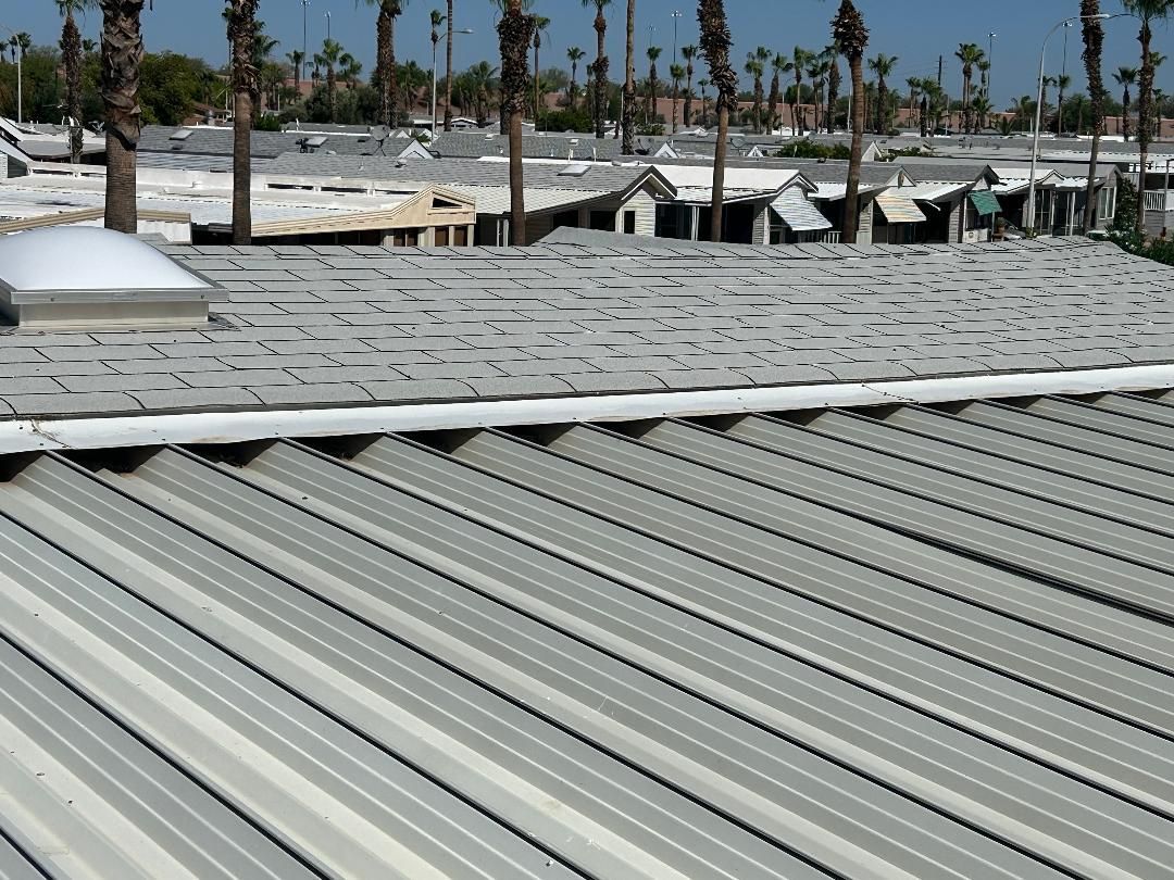 Corrugated metal roof in the foreground with palm trees and white buildings in the background