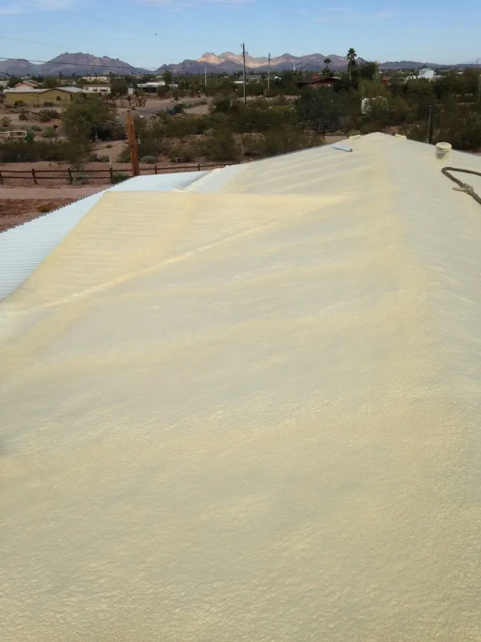 Large white tarp or roof covering on a hillside, with desert landscape and mountains in the distance