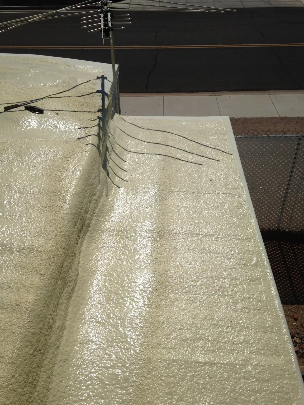Close-up of a textured cream roof seam with several dark cracks near the edge