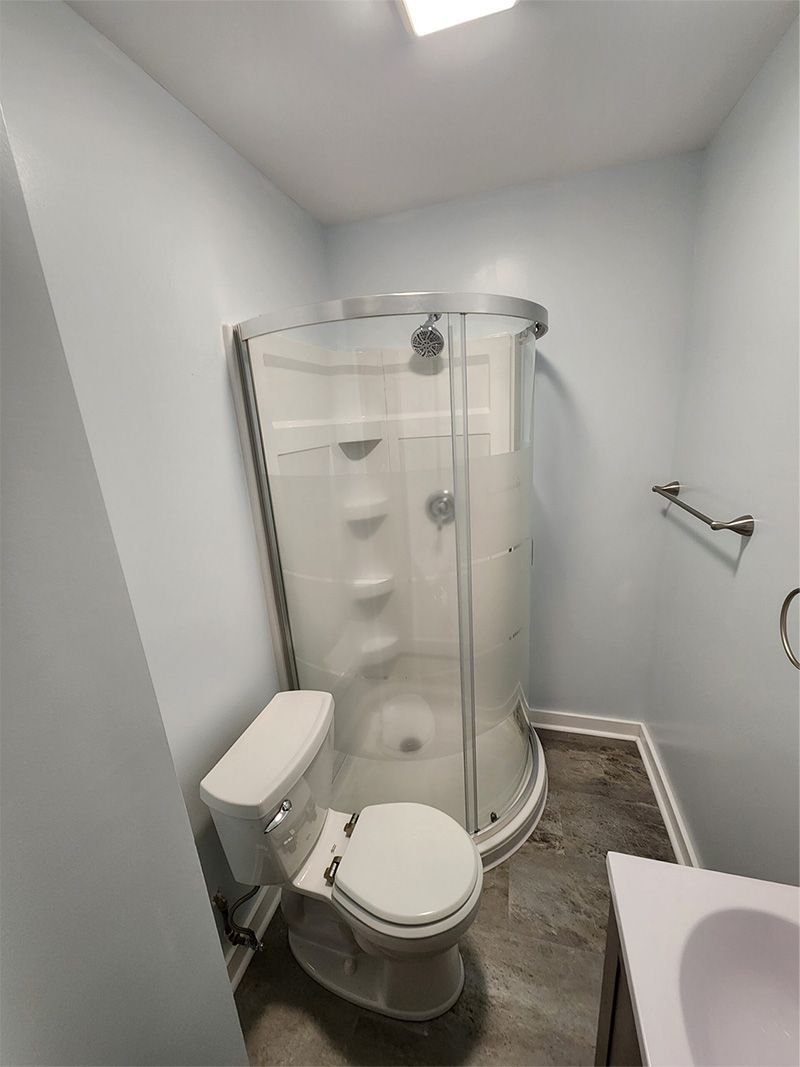 A bathroom with a toilet , shower and sink.