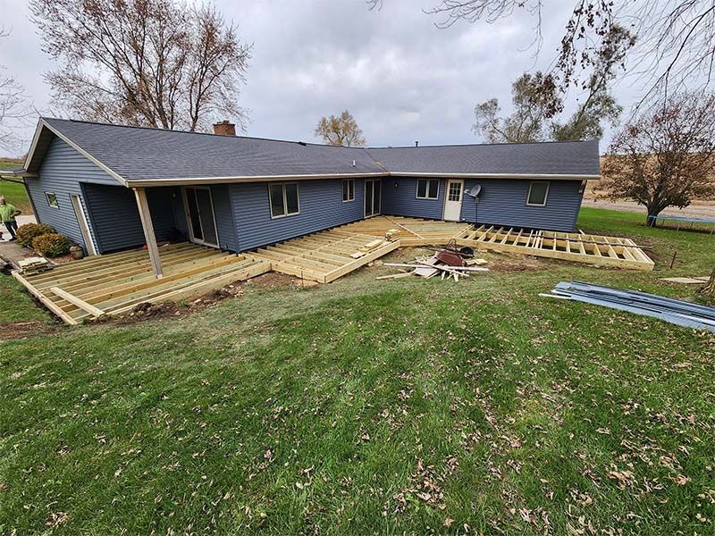 A blue house with a wooden deck in front of it.