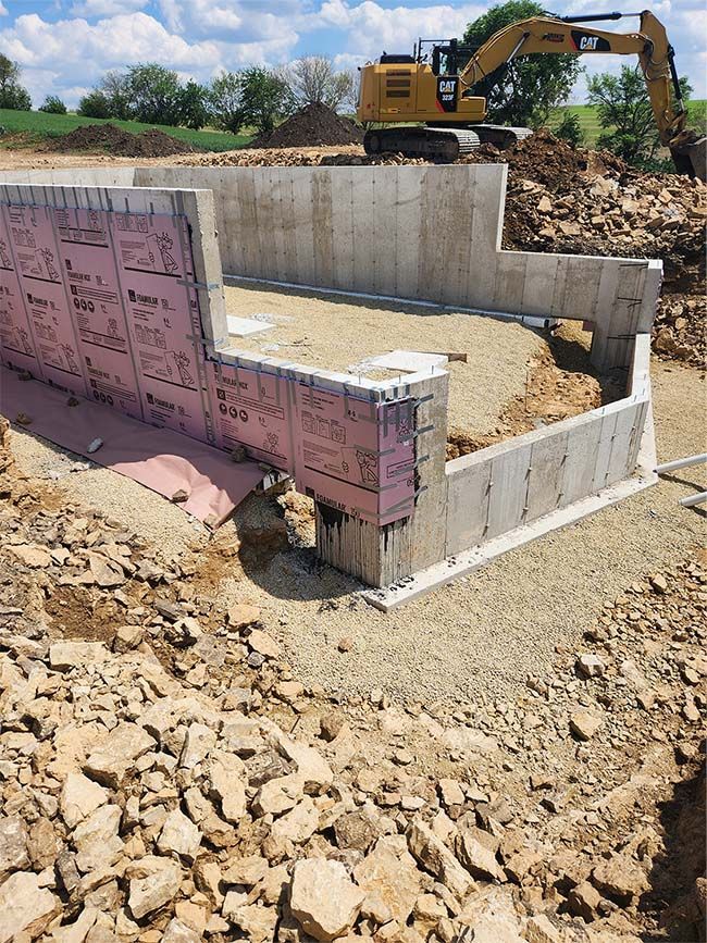 A concrete wall is being built in a pile of rocks with a bulldozer in the background.