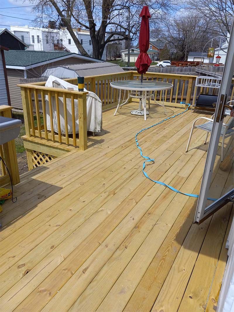 A wooden deck with a table and chairs and an umbrella.