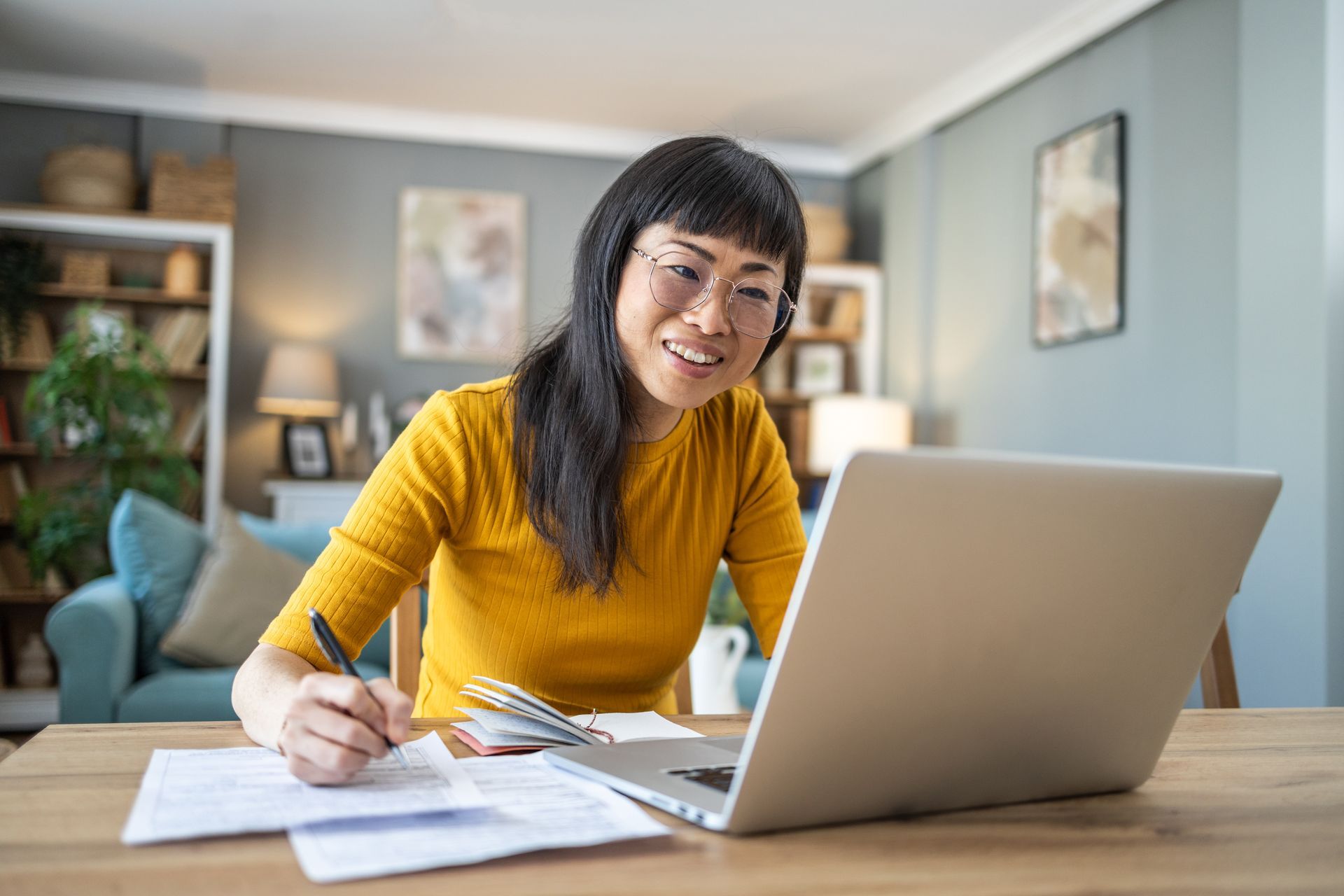 A woman is working from home and sitting at a table using a laptop computer.