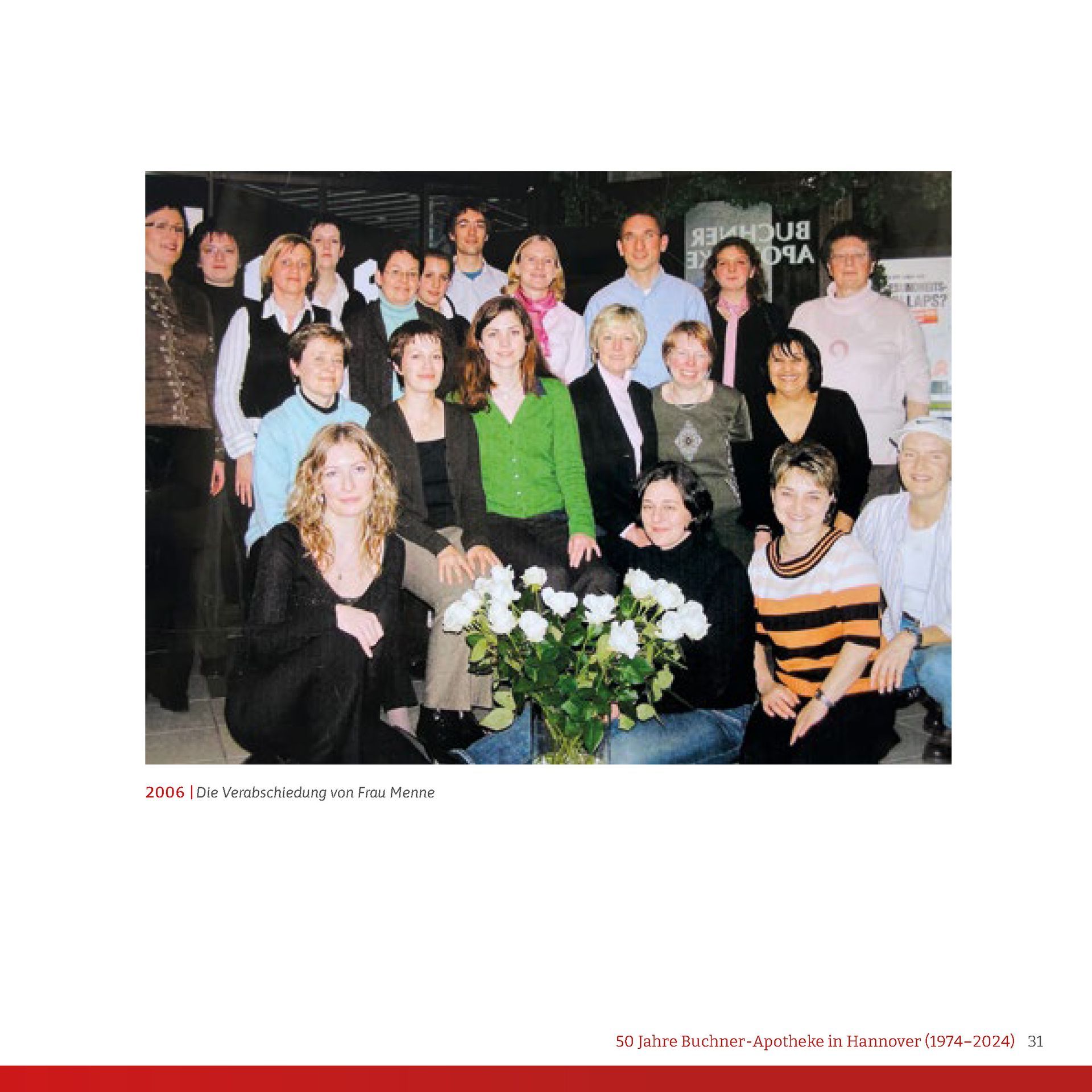 Eine Gruppe von Menschen, die für ein Foto posieren, mit einer Vase mit Blumen in der Mitte