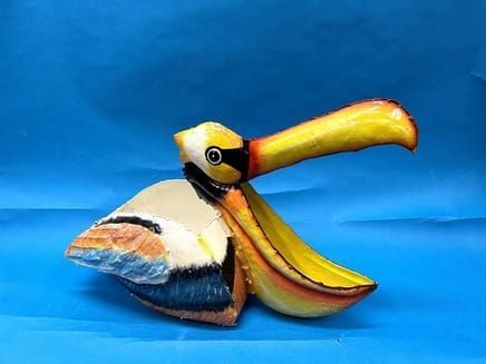 Colorful bird sculpture with a long yellow beak on a blue background