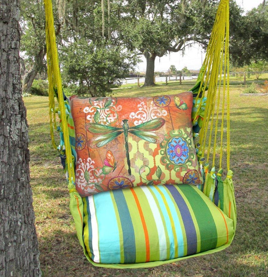 Vibrant Porch Swing chair with cushions Colorful striped swing seat with orange floral back cushion hanging outdoors on a tree lawn