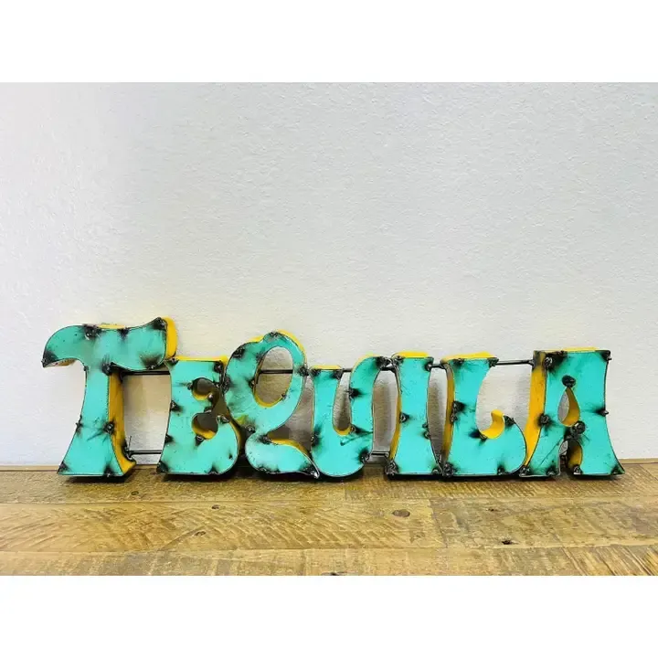 Turquoise and black decorative “Tough” sign on a wooden surface against a white wall