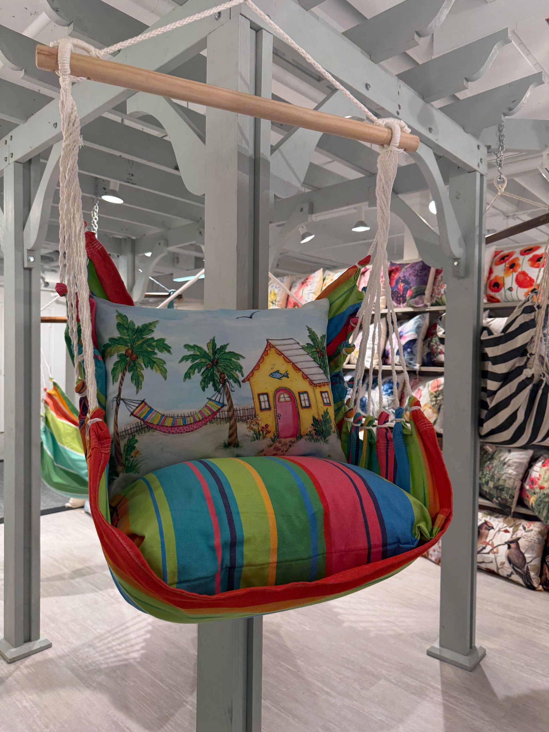 Colorful hanging hammock chair with palm tree print and striped cushion in a home decor store