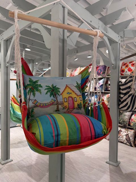Colorful hanging hammock swing chair with palm tree print and striped cushion at Island Vibes home decor store