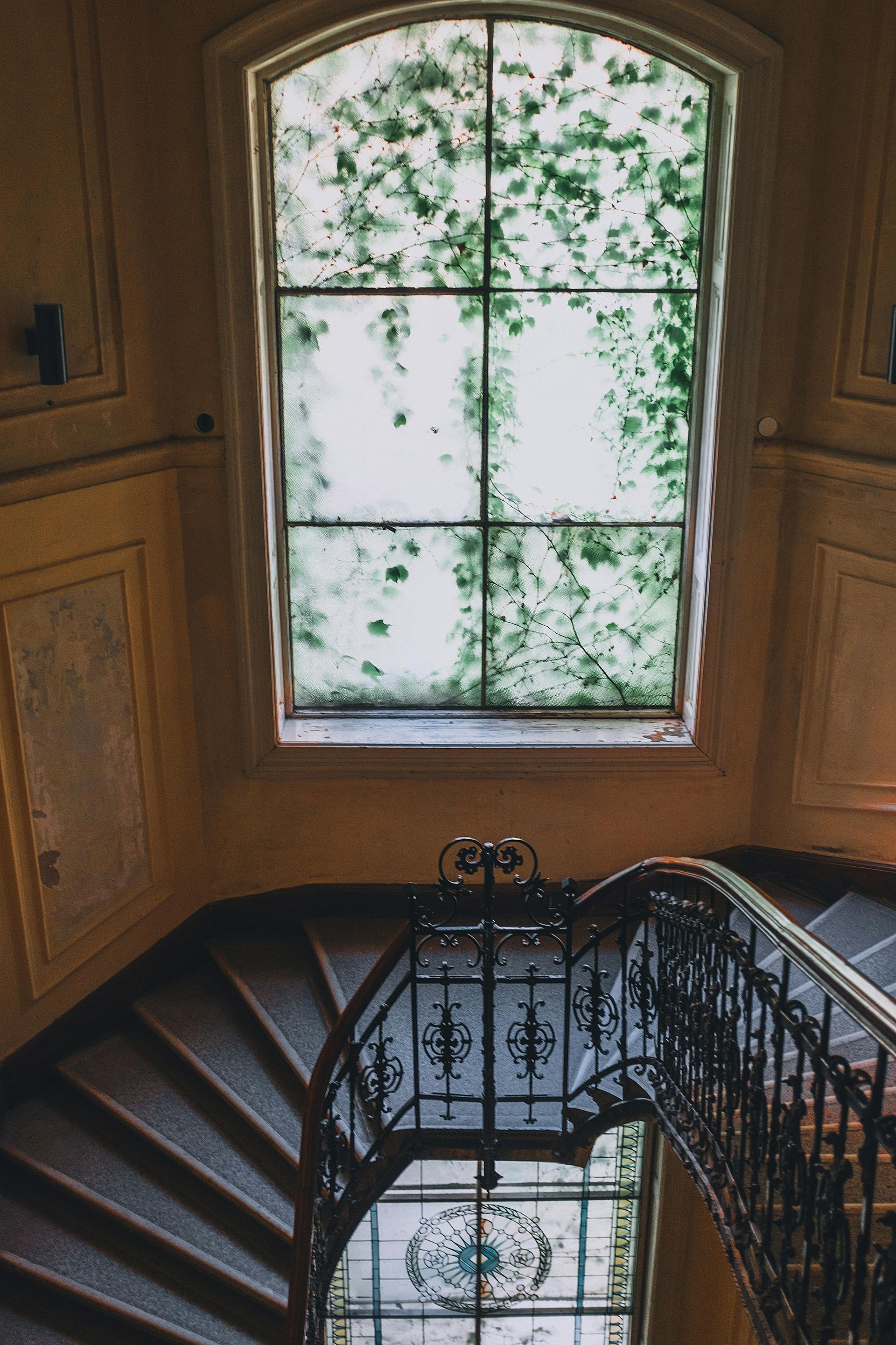 A staircase with a stained glass window and a wrought iron railing