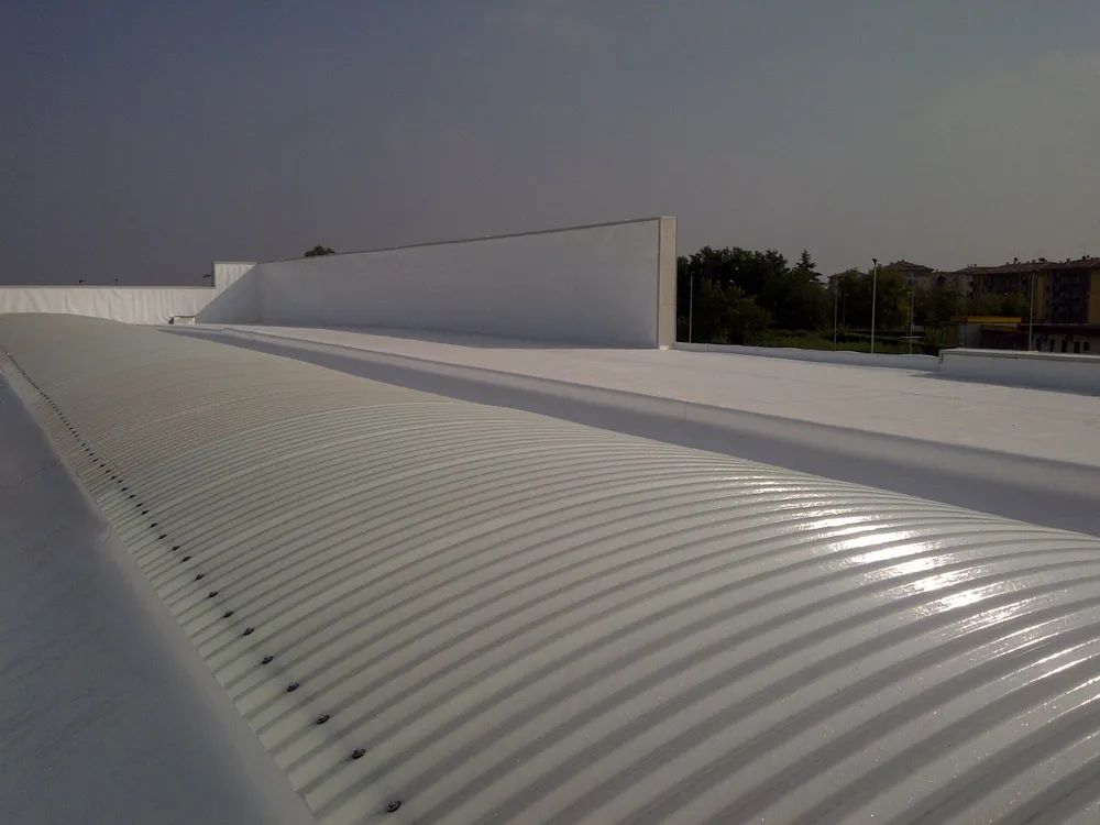 Tetto bianco ondulato accanto a un alto muro bianco sotto un cielo limpido