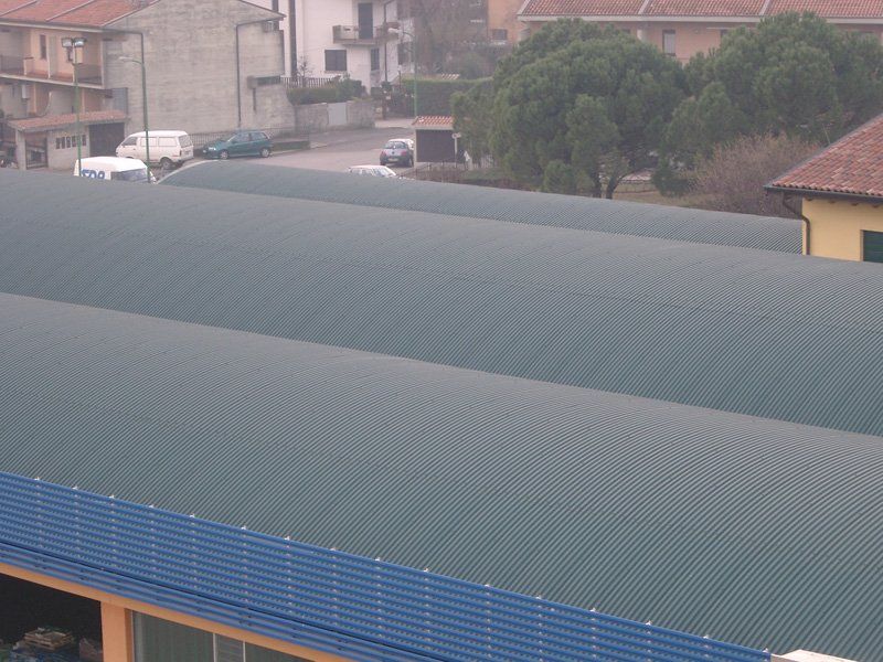 Grande edificio con tetto verde e parete inferiore blu, visto dall'alto in una zona residenziale.