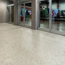 A polished, light-colored speckled floor in front of glass doors opening into a conference hall.
