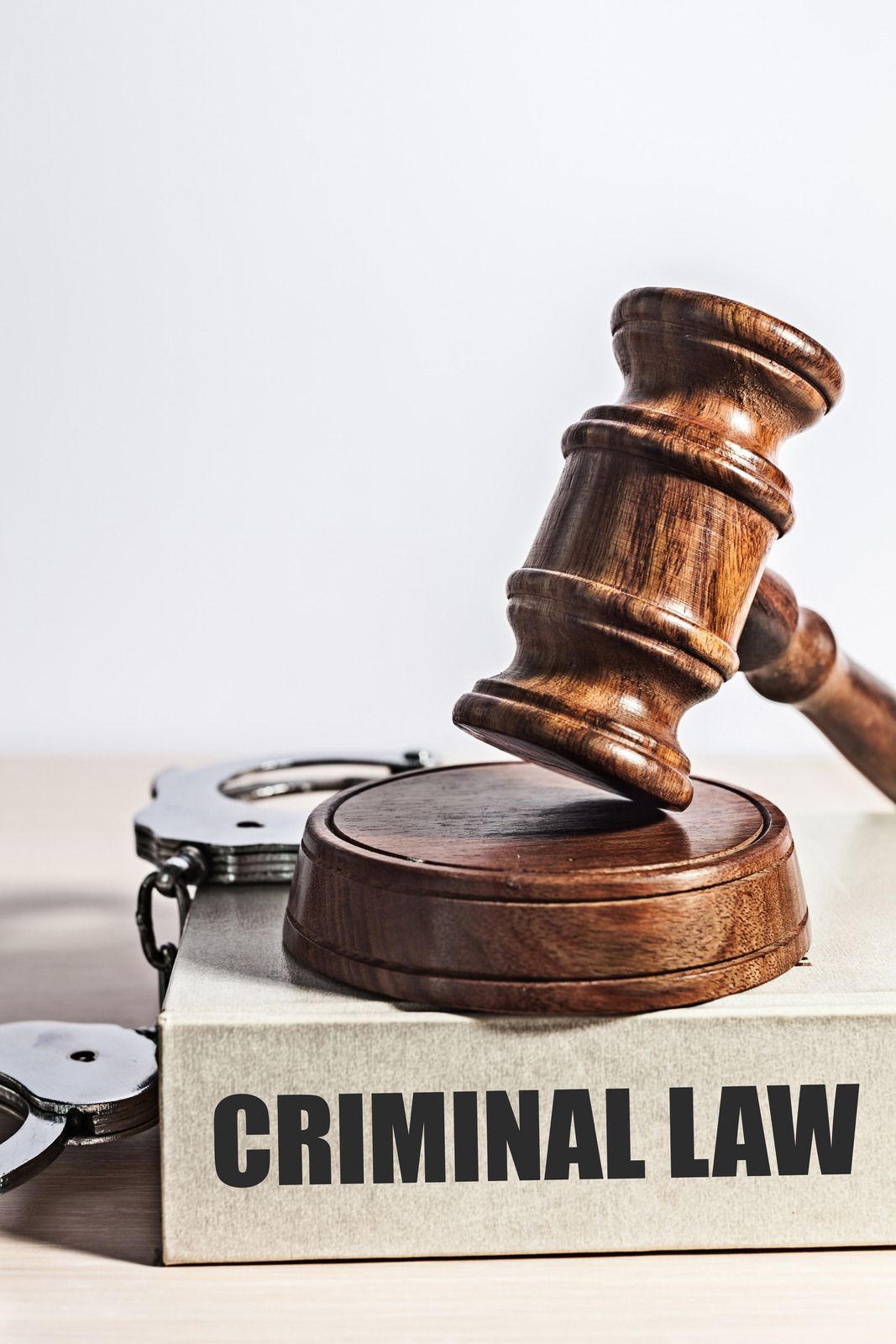A wooden judge 's gavel is sitting on top of a book titled criminal law.