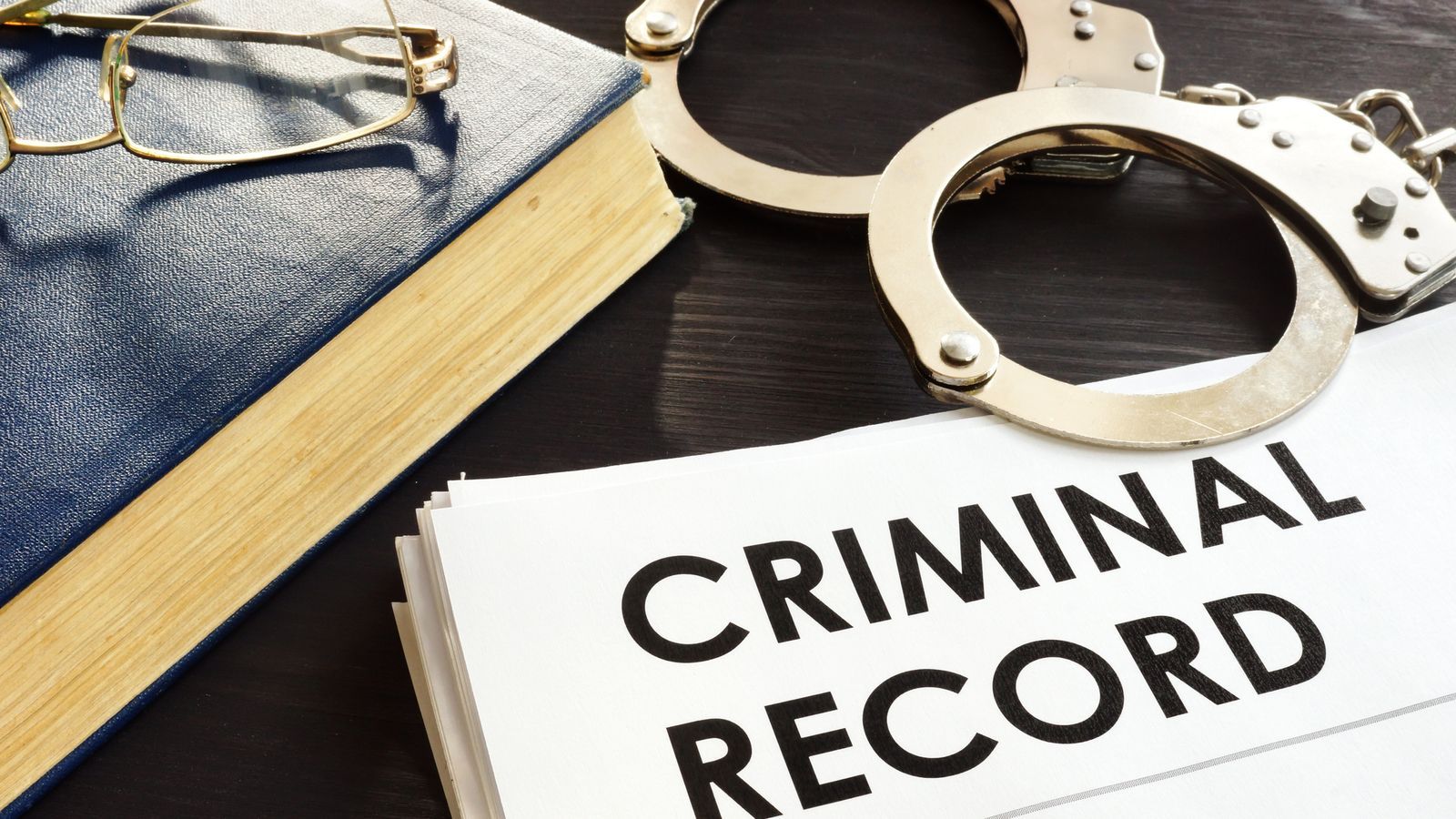 A judge 's gavel is sitting next to an alarm clock and a piece of paper that says criminal records.