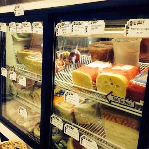 Bakery display case with assorted cakes and pastries, including sliced rolls and layered desserts.