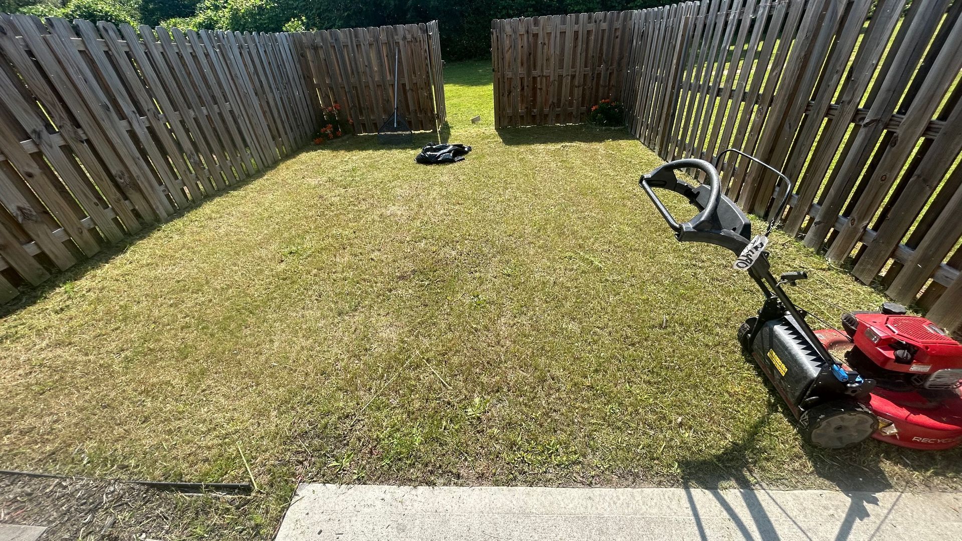 Small yard enclosed by wooden fences; lawnmower in the corner.