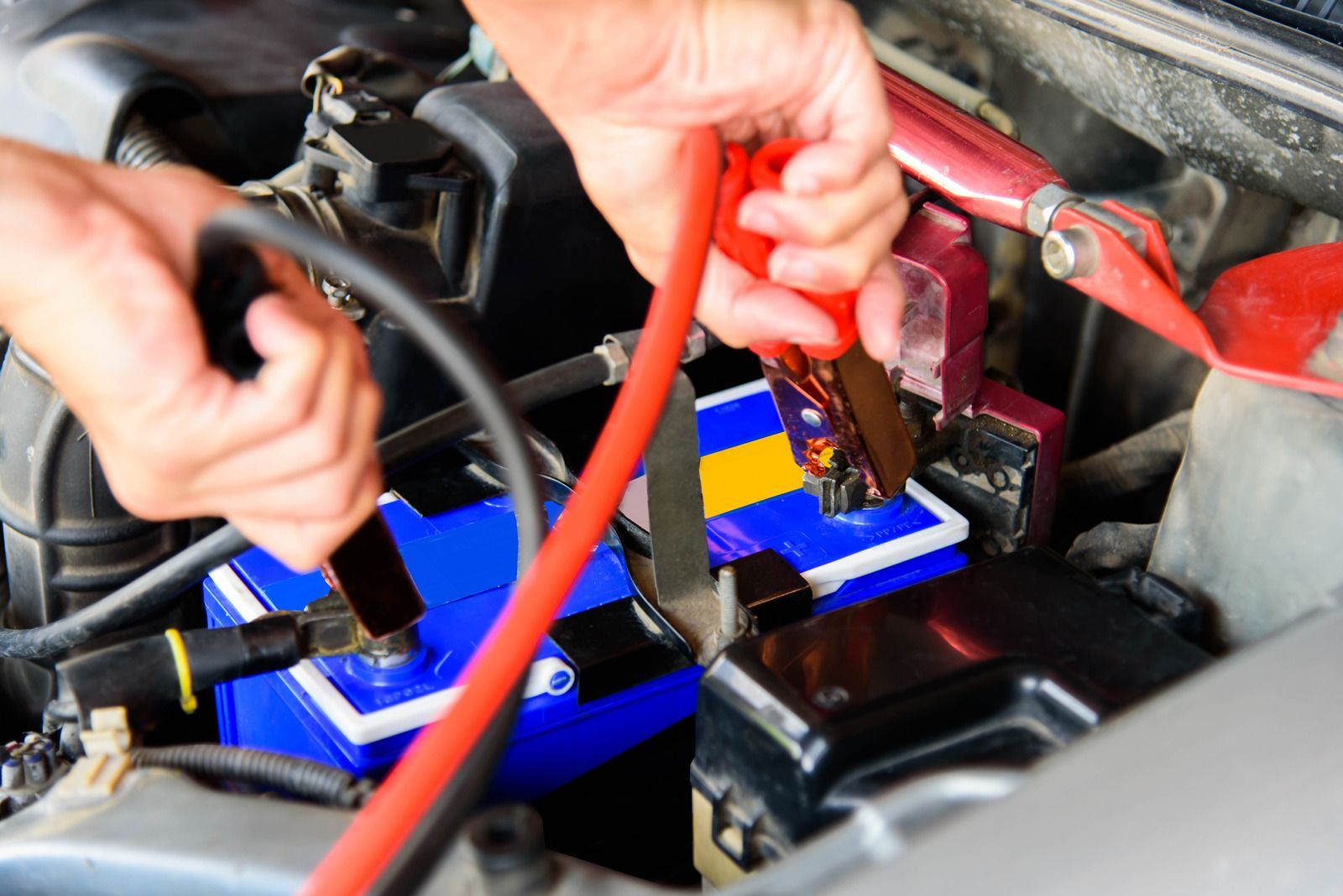 Person examining damage on a blue car door. Holding a small tool, outdoors.
