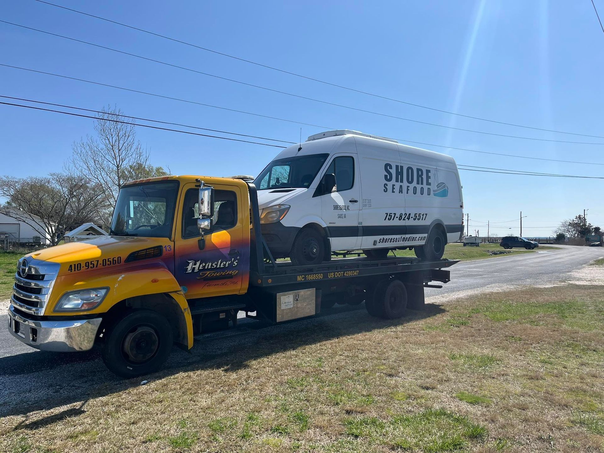 Yellow tow truck carrying a white van with 