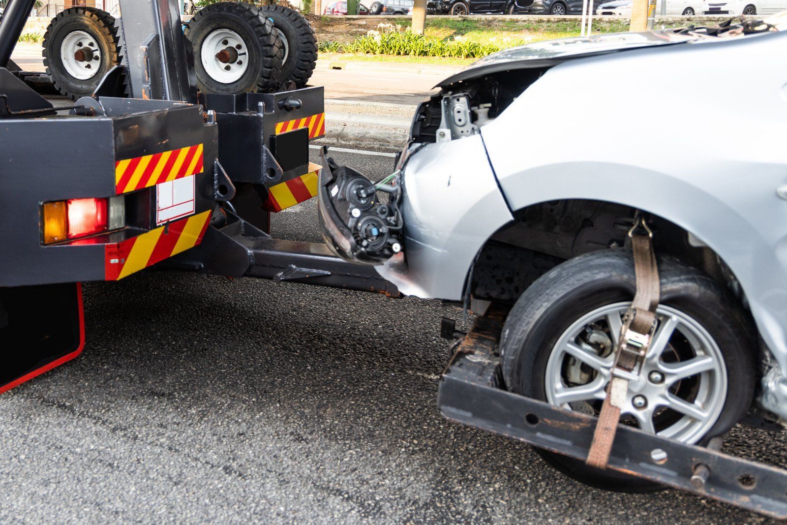 Damaged silver car being towed by a tow truck after a car accident.