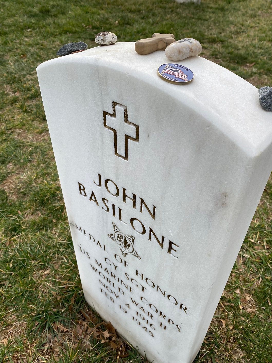 Headstone of John Basilone with the Medal of Honor, topped with painted rocks.