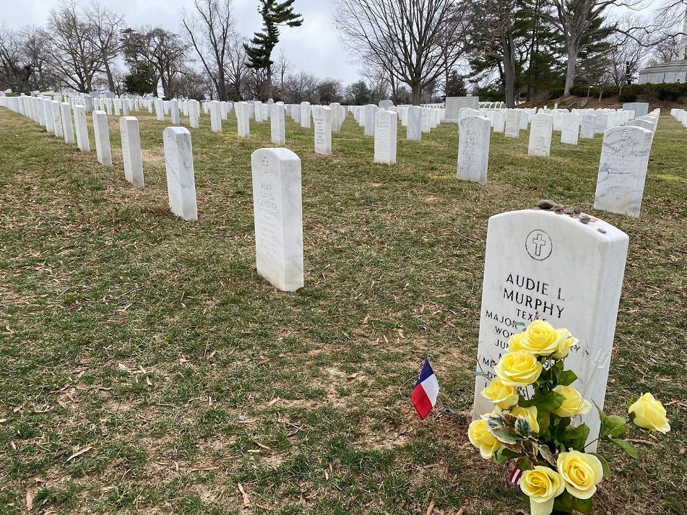 Rows of white gravestones in a cemetery, with a headstone labeled 