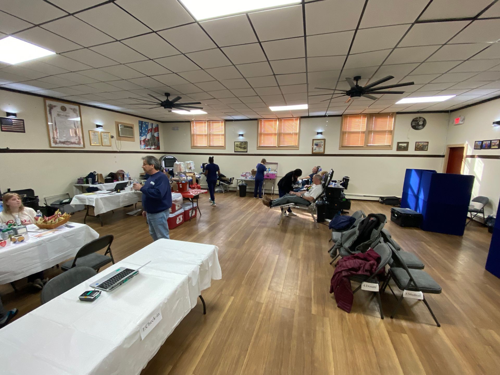 People donating blood at a blood drive in a large room.