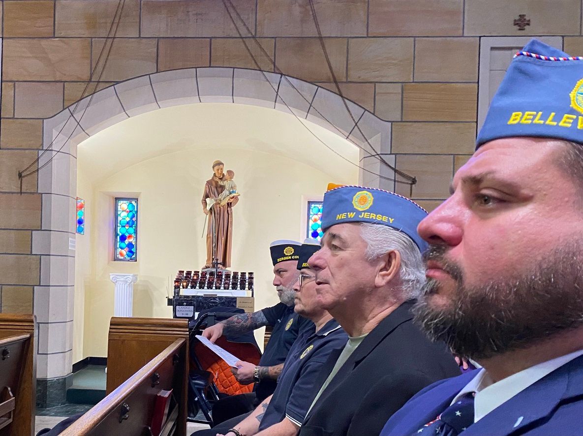 People in blue hats at a church service; a statue is visible in the background.