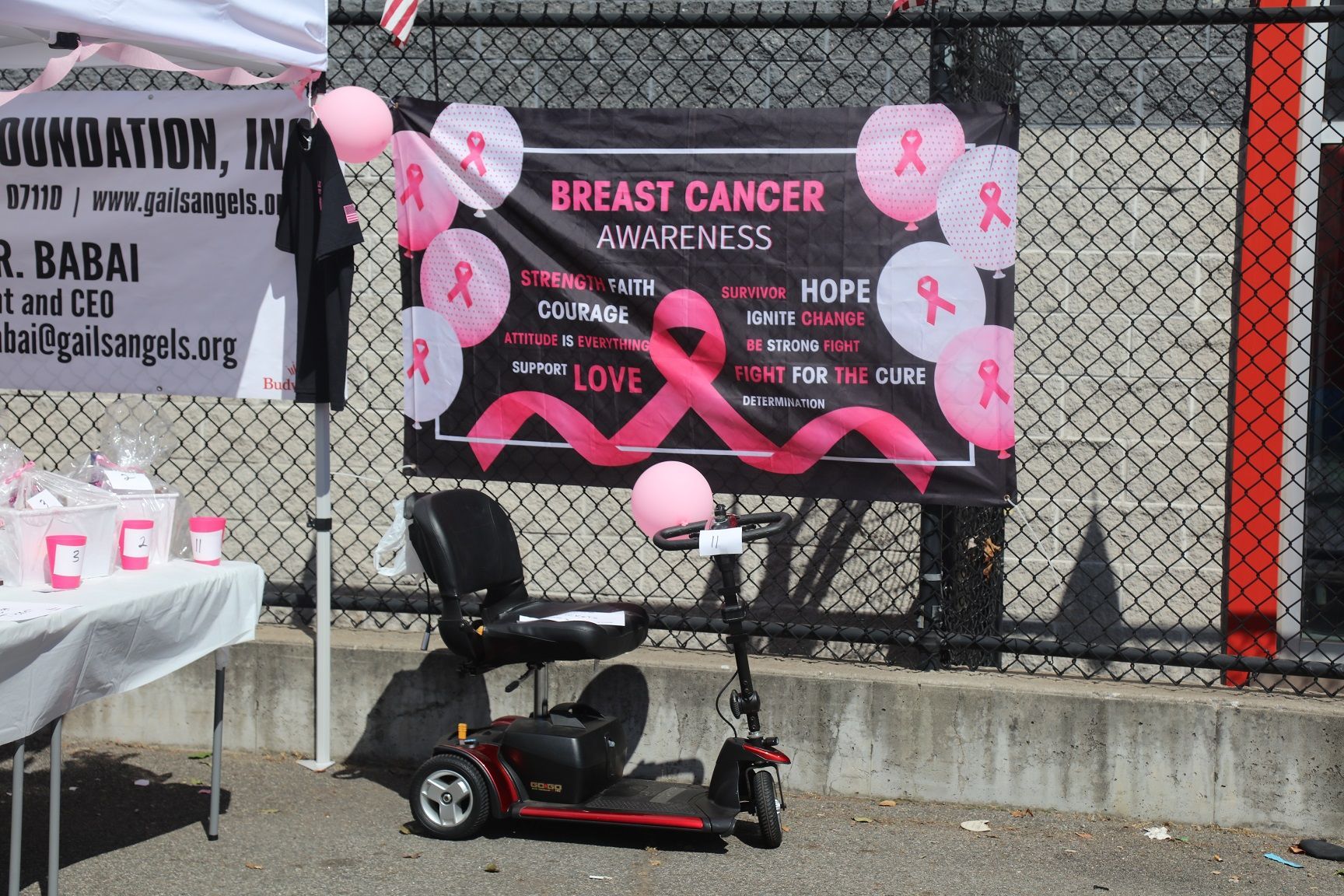 Breast Cancer Awareness event with banner, balloons, and mobility scooter.
