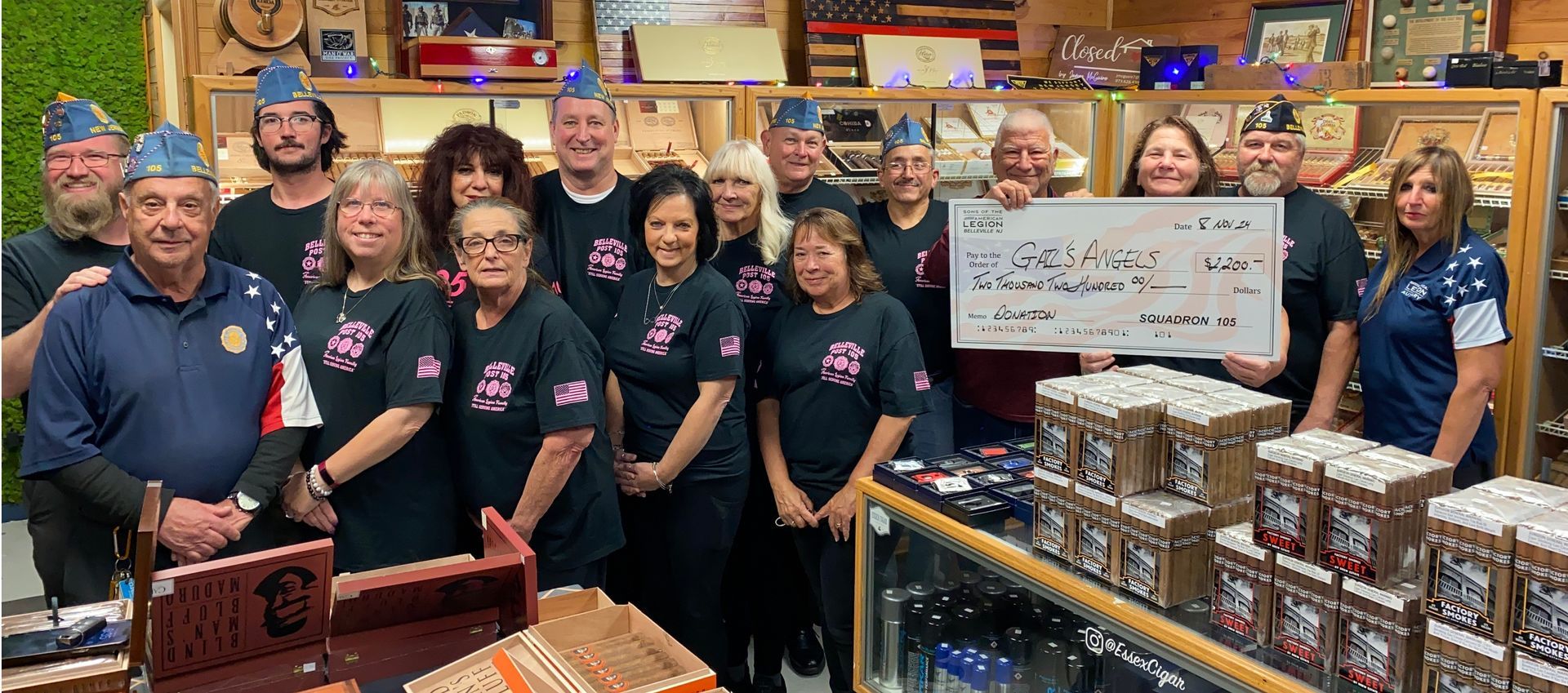 A group holding a large check, standing in a shop. They are likely veterans.