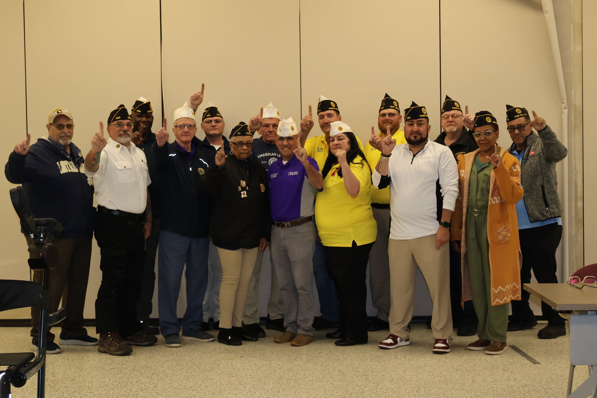 Group of people posing indoors, some in costumes and hats, with one person holding a yellow flag.