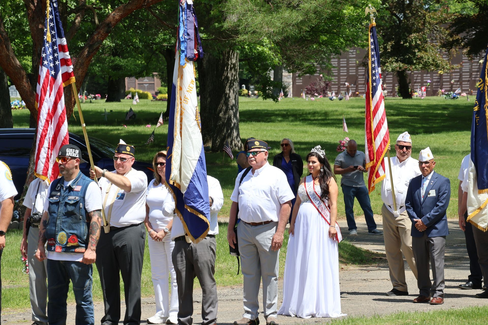 People standing in a park holding American and state flags during a ceremony