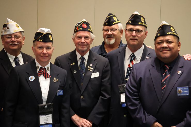Group of veterans in uniform with caps, smiling at a conference.