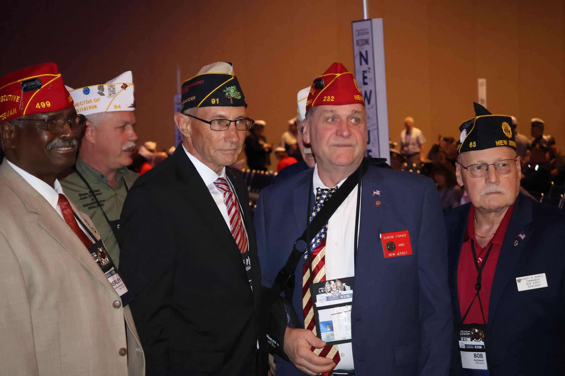 Veterans wearing caps and suits at a conference in Nevada, with a sign in background.