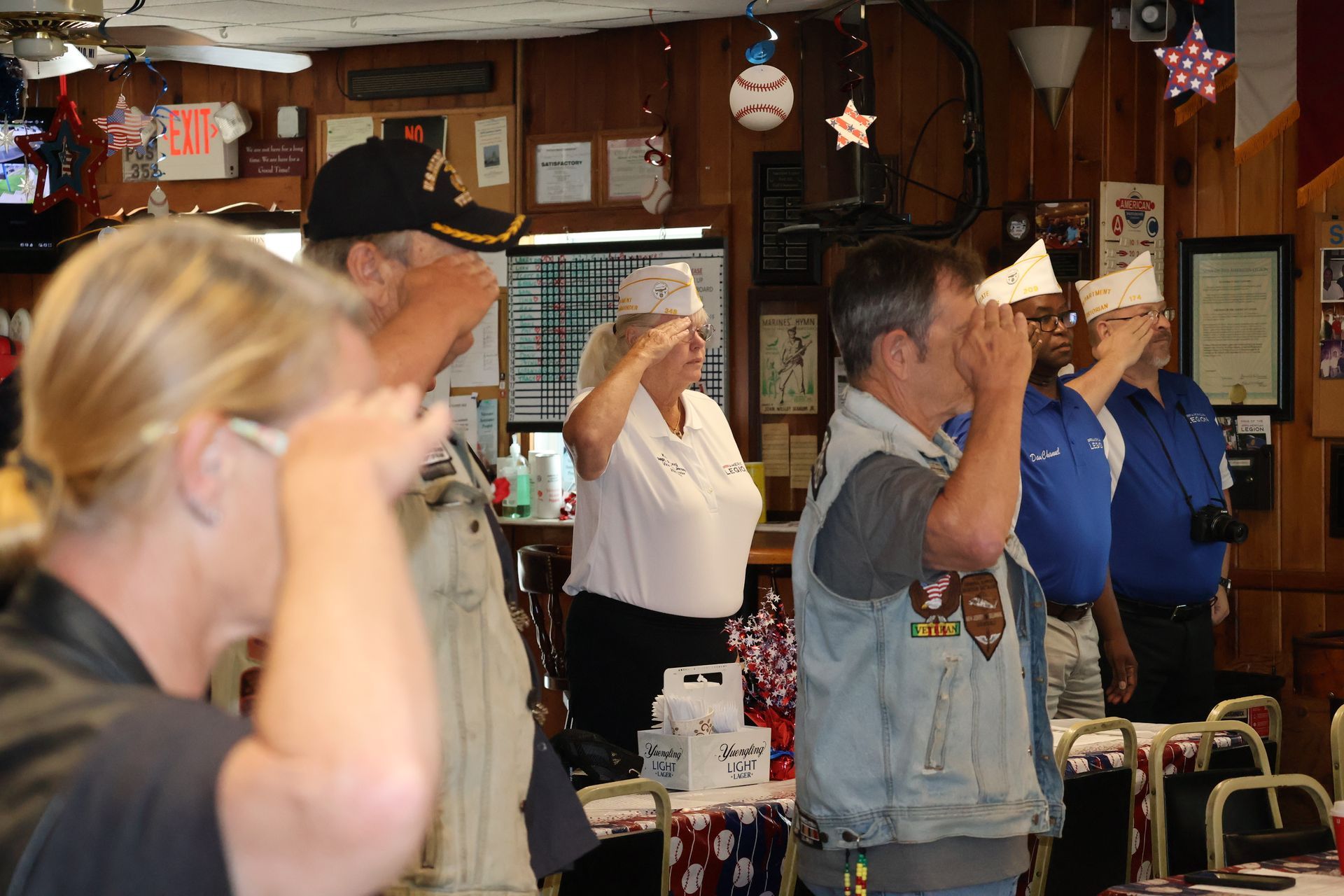 People saluting indoors, likely a patriotic event.