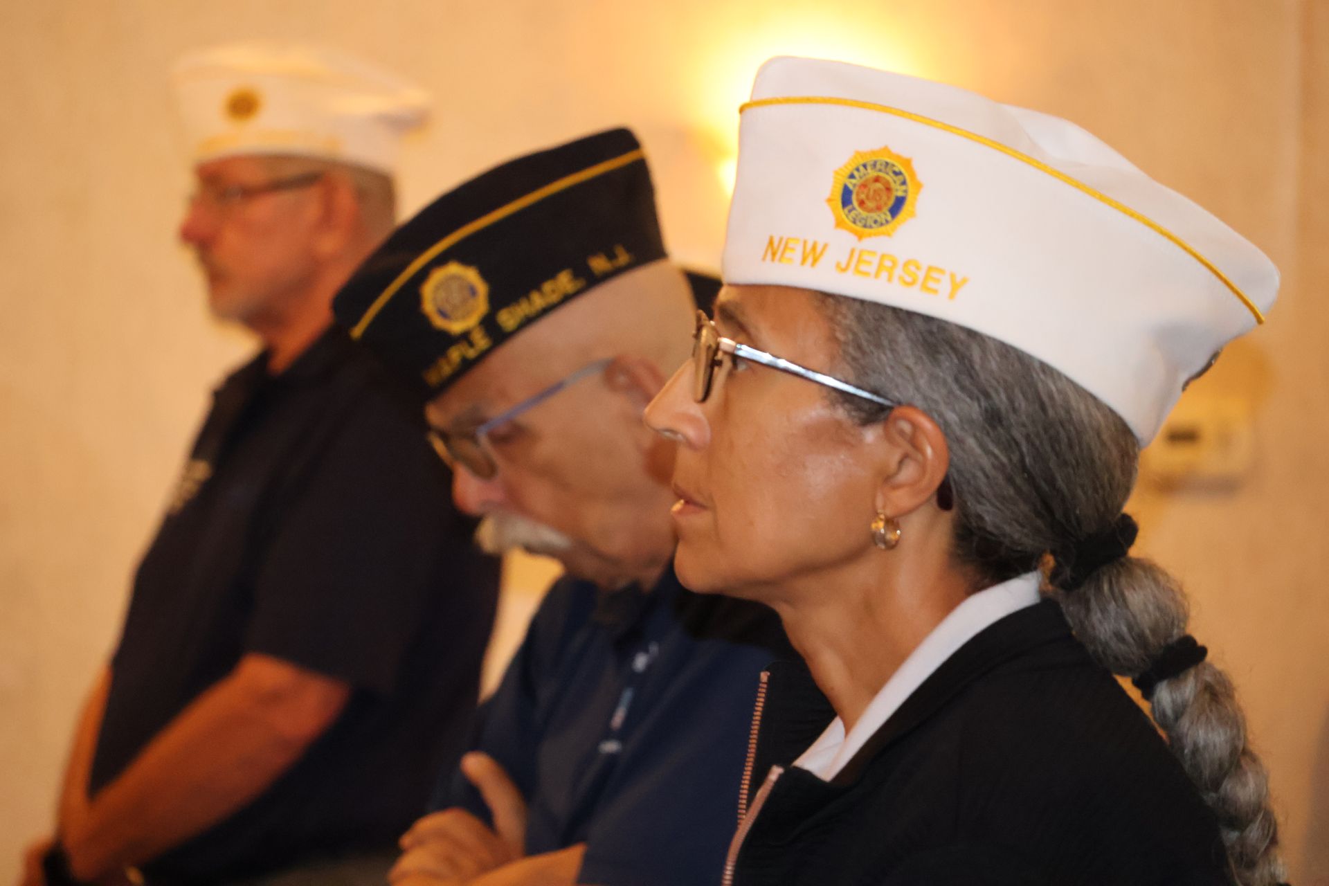 Three people in uniform hats, standing and looking down. 