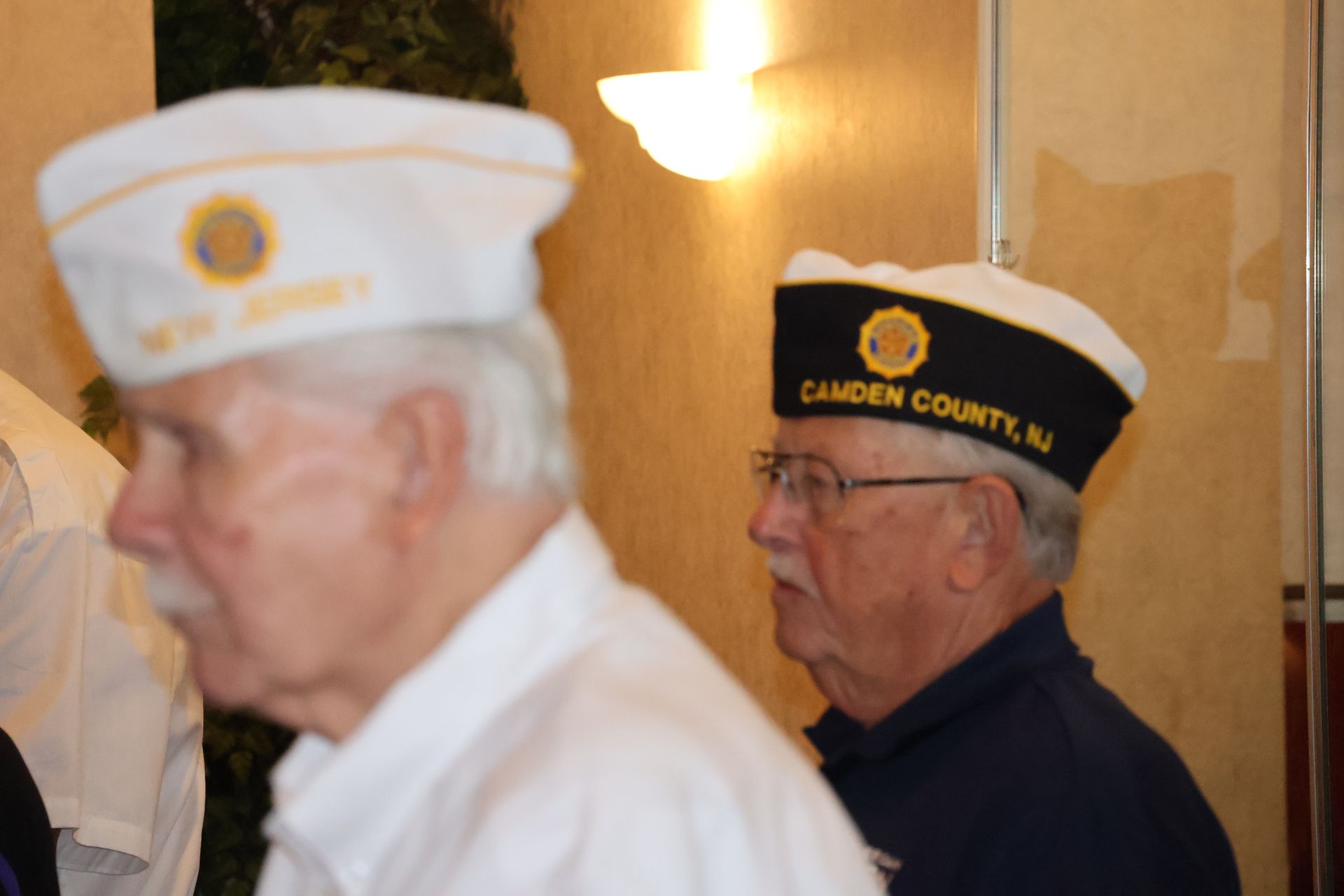 Two men wearing white hats with insignias. One reads 