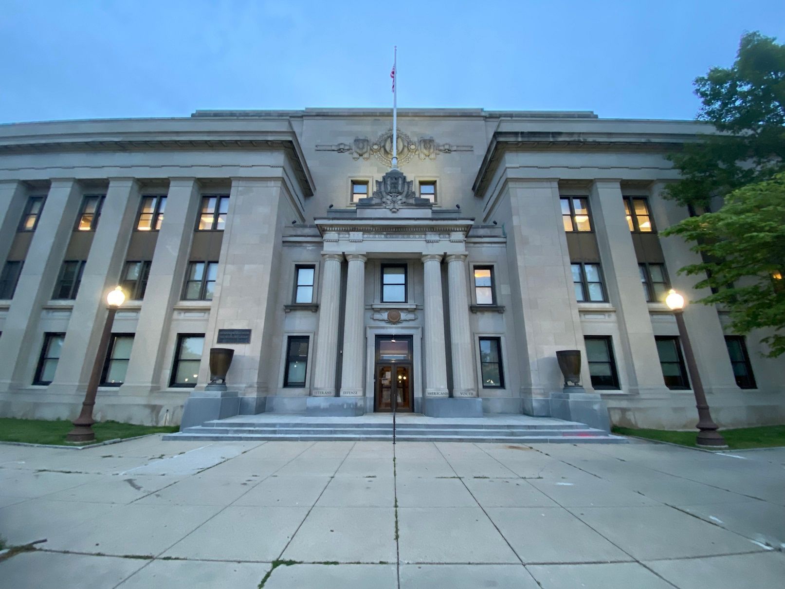 Stone building with steps, columns, and a flagpole. Dusk setting.