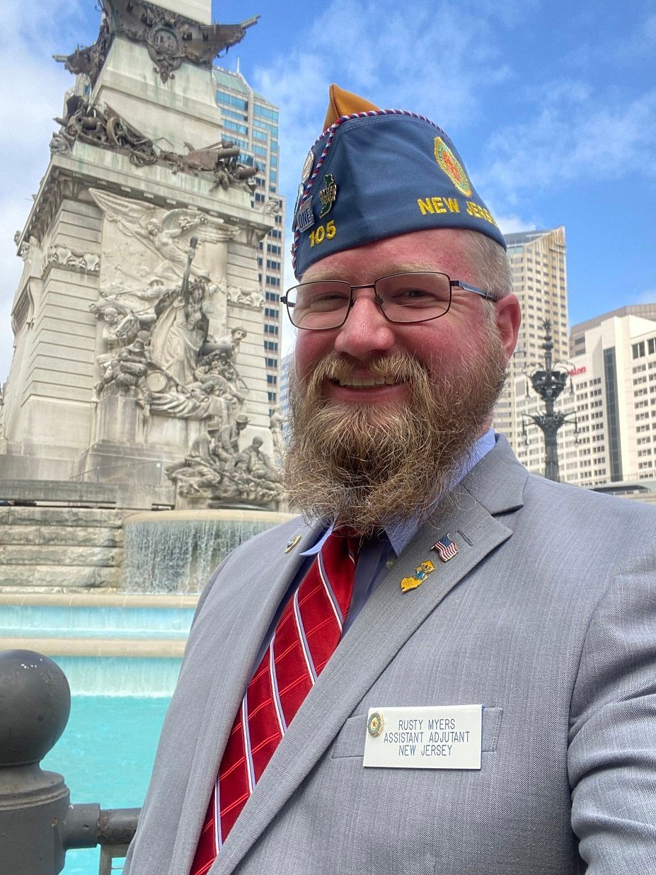Man in VFW uniform smiles in front of a fountain and monument in downtown Indianapolis.