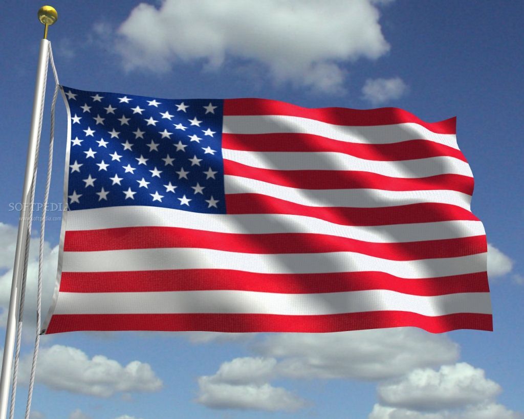 American flag waving in the wind against a partly cloudy blue sky.