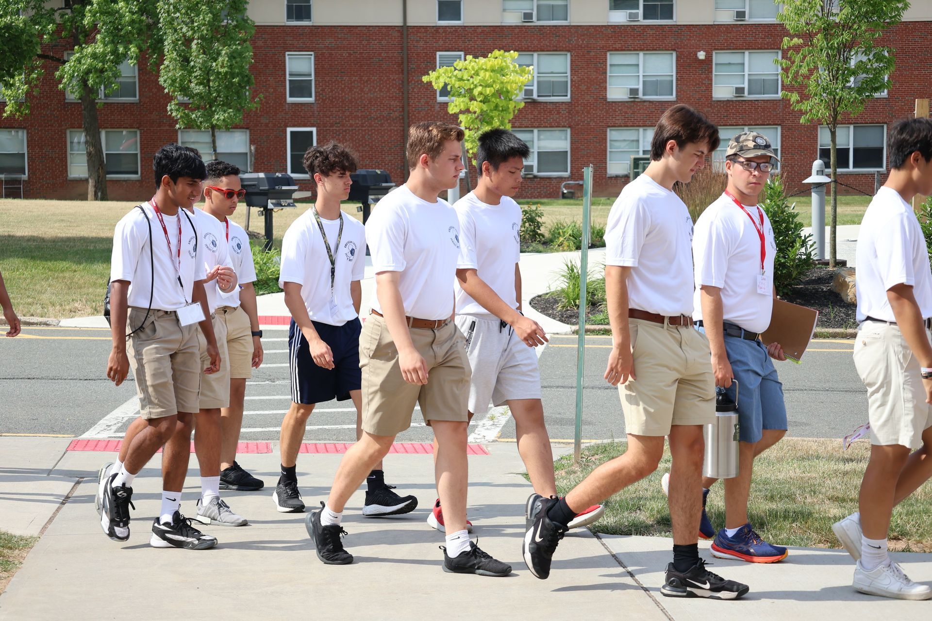A group of young people in white shirts and shorts walking outside.