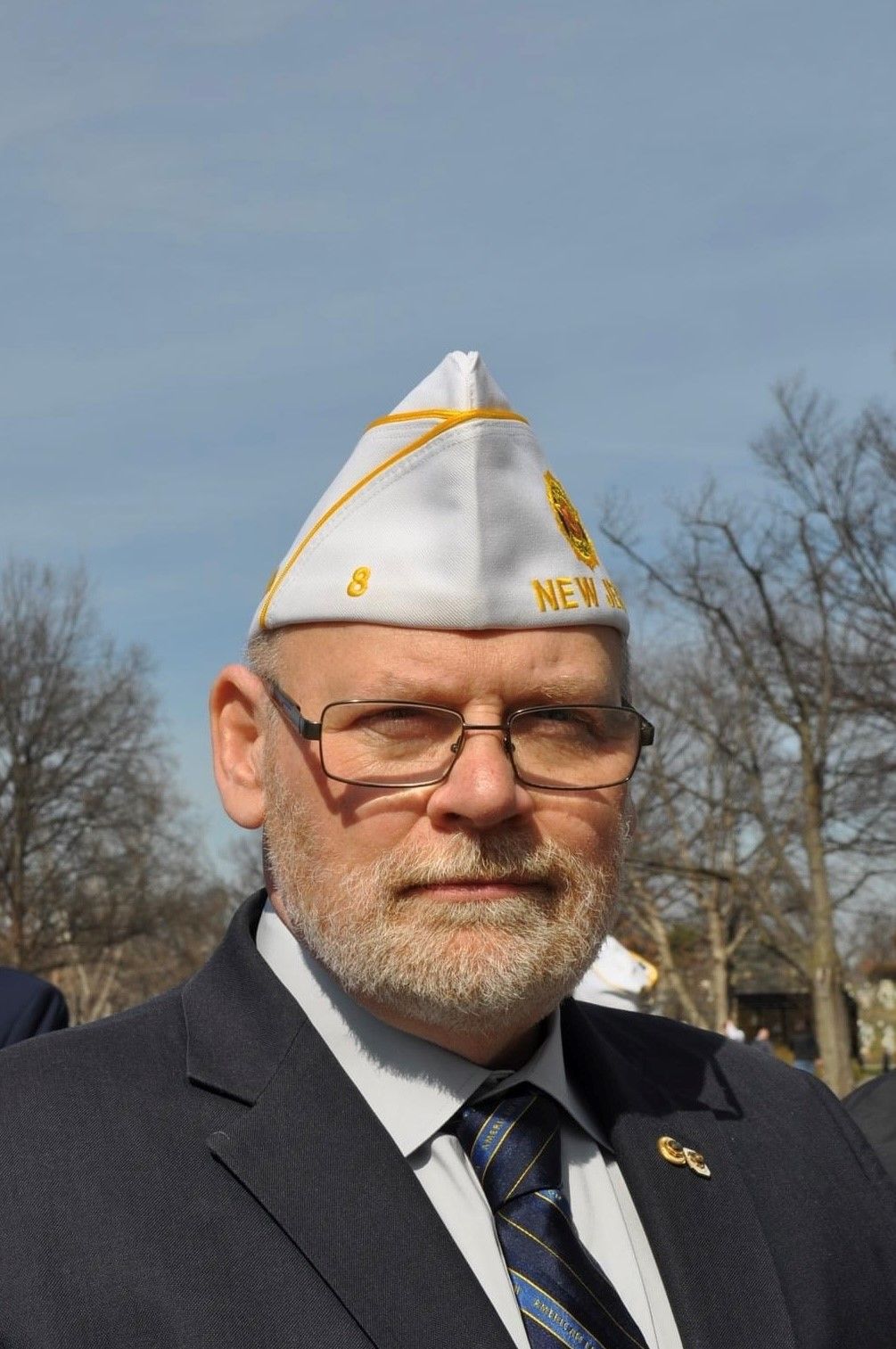 Man in navy blazer and Veterans of Foreign Wars hat, looking at the camera outdoors.