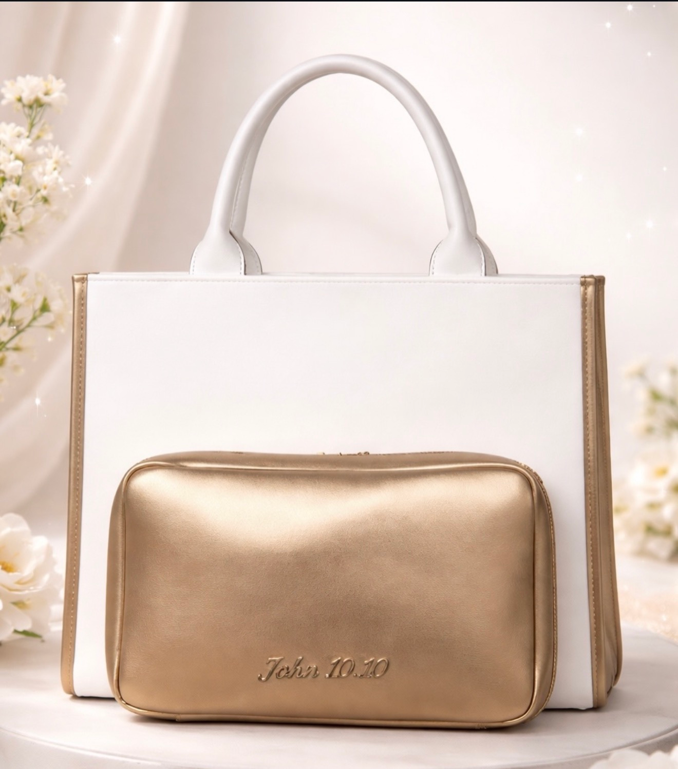 White handbag with gold trim and matching gold zip pouch on a soft floral background