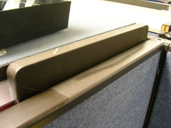 Close-up of a brown padded seat divider with a blue carpeted surface behind it.