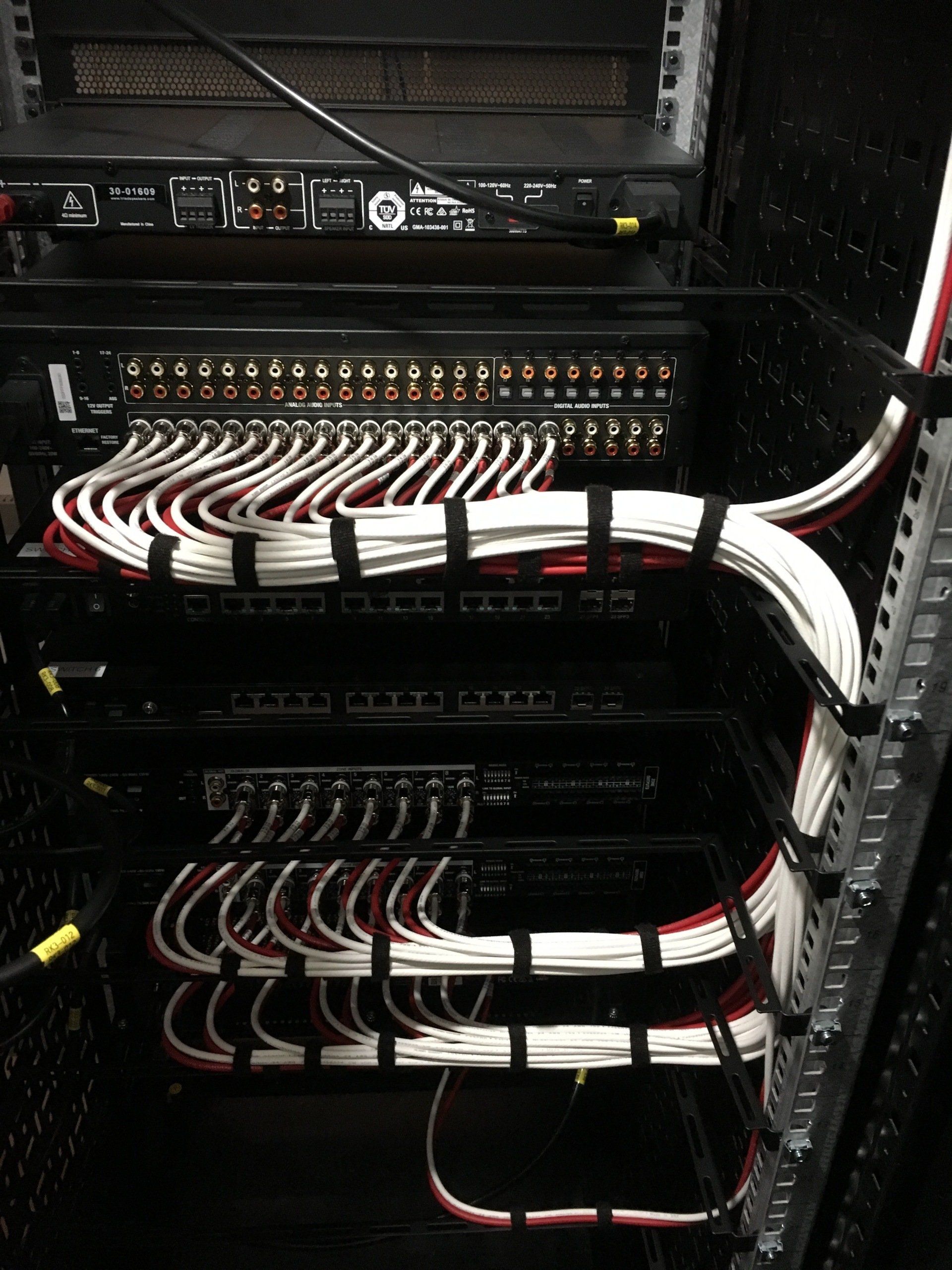 Black server rack with neatly organized white and red cables secured with velcro straps.