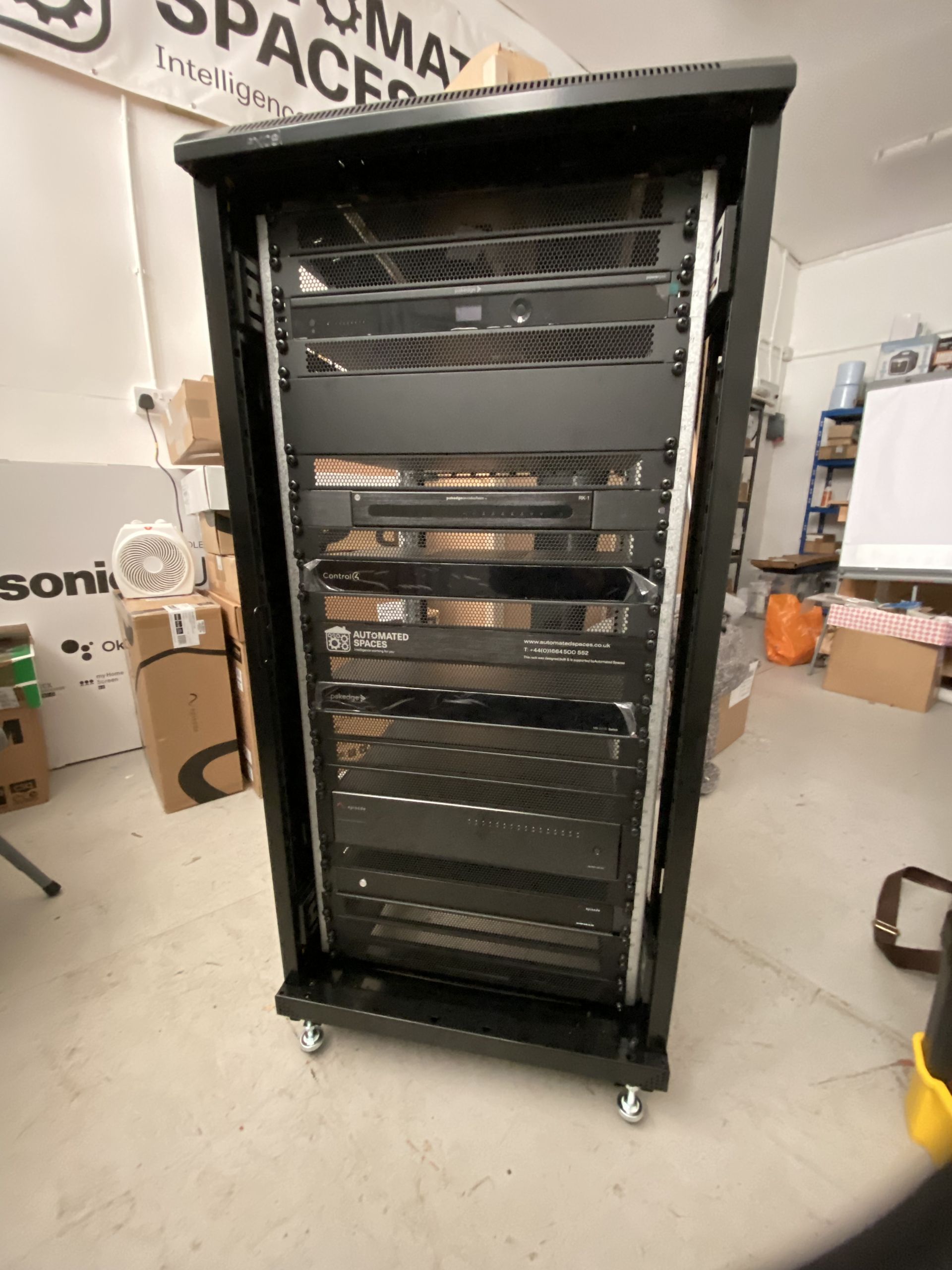 Black server rack on wheels, containing electronic equipment in a room.