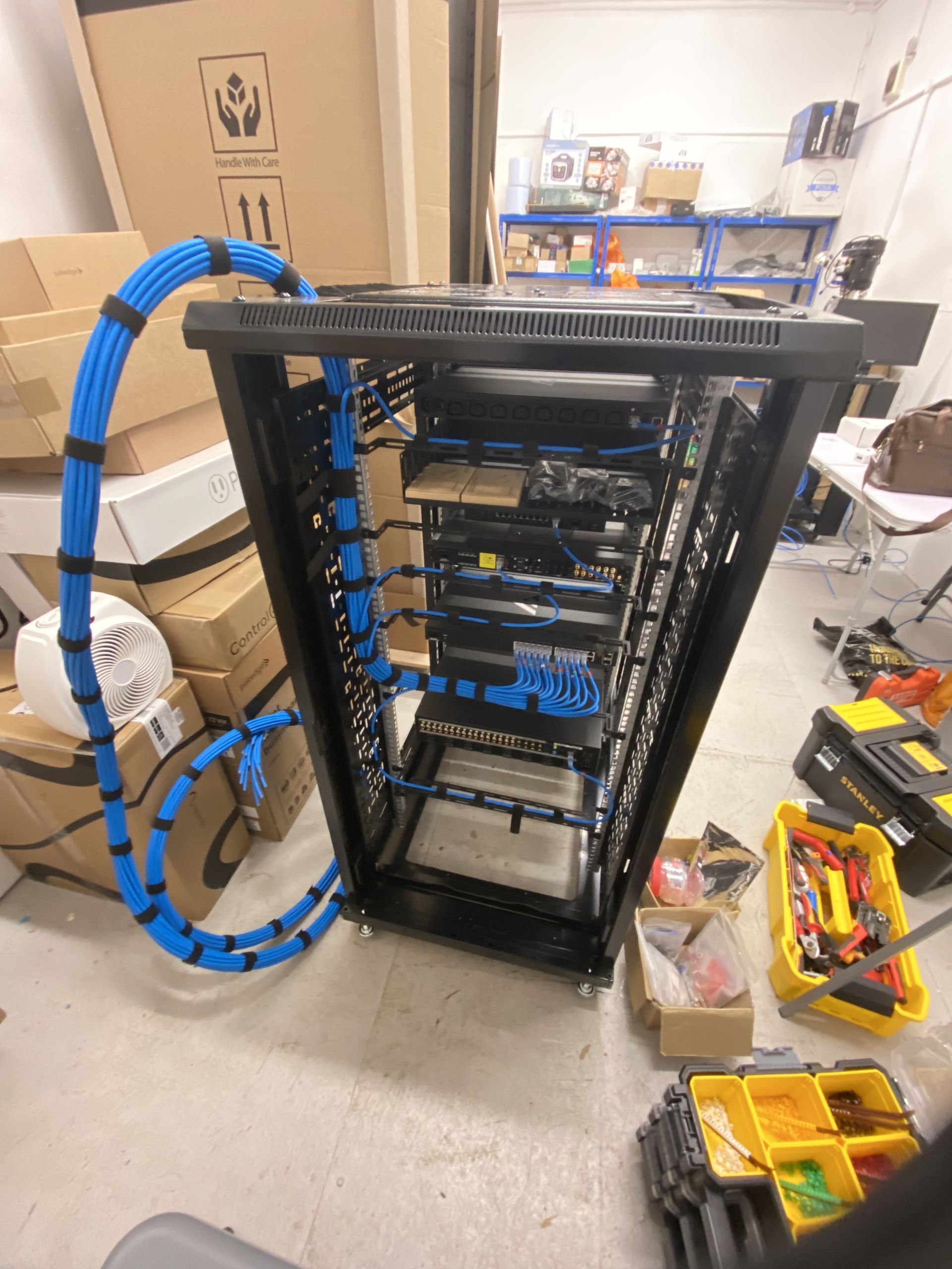Server rack with network cables, in a workshop. Blue cables are bundled.