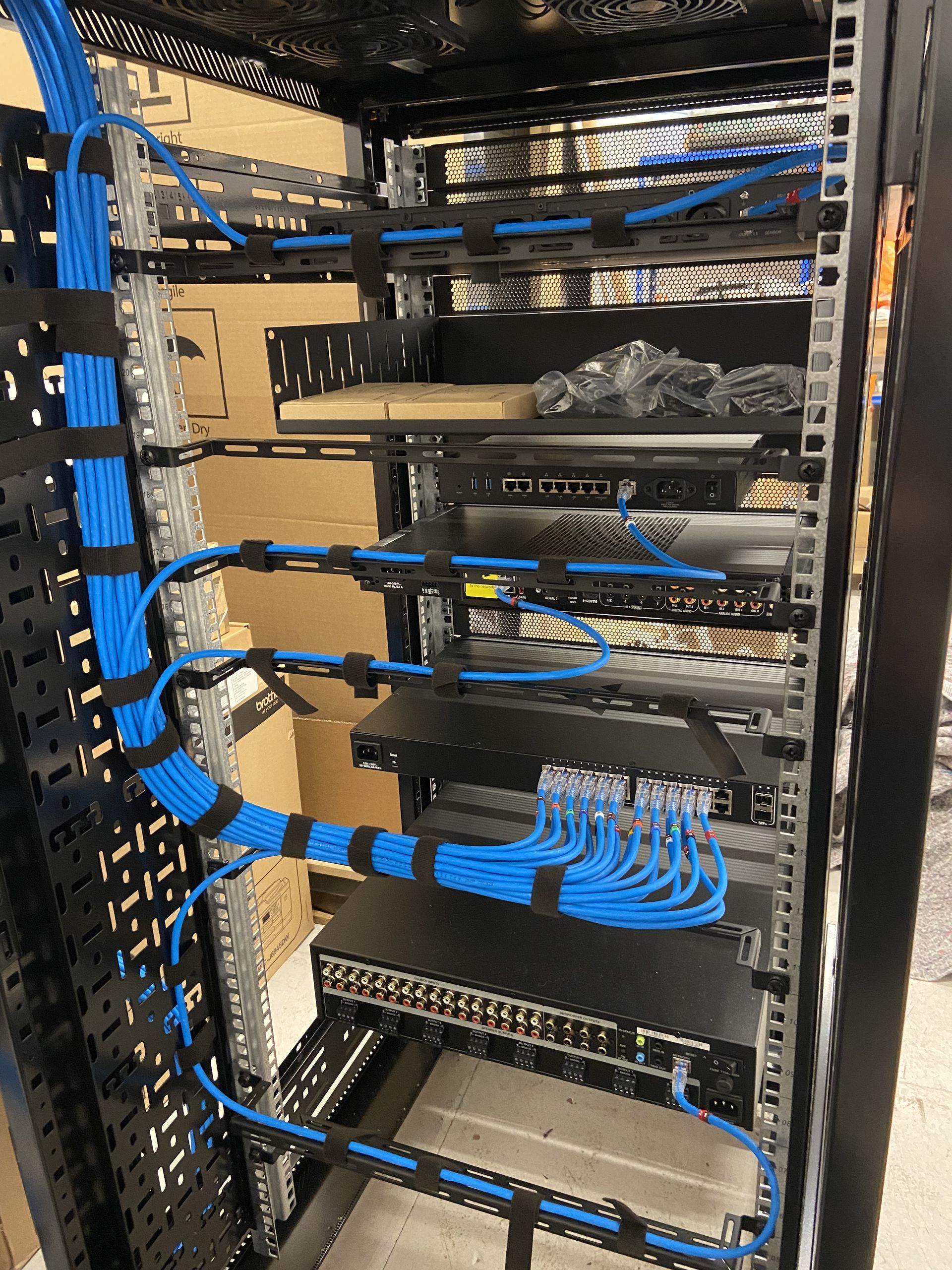 A black server rack filled with blue network cables, neatly organized with velcro straps.